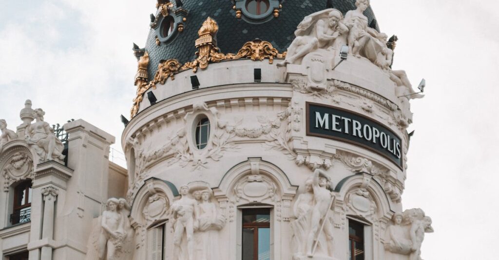 Iconic Metropolis Building dome in Madrid captured in daylight, showcasing intricate architectural details and sculptures.